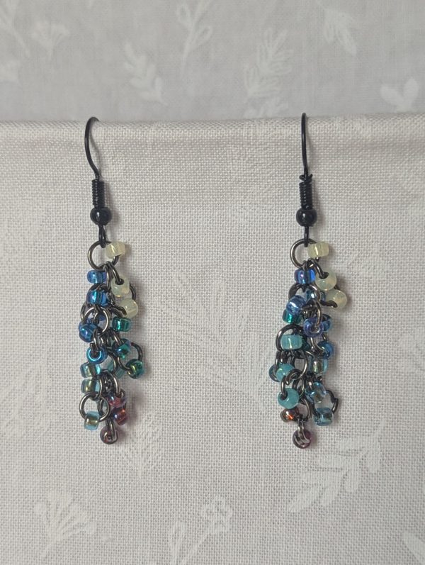 Starlight Drift Earrings: Handmade metallic galaxy earrings with 21 multicolored beads in seven cosmic shades, black hooks, and tungsten-toned jump rings.