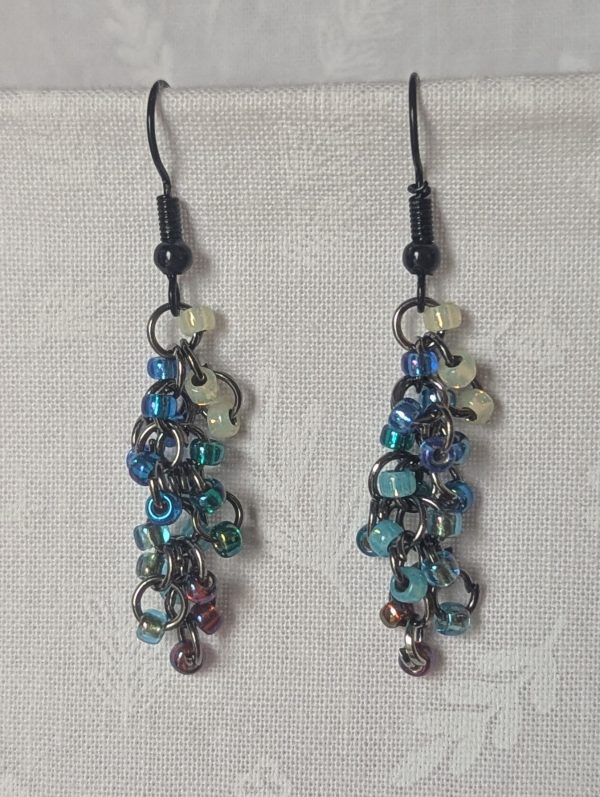 Starlight Drift Earrings: Handmade metallic galaxy earrings with 21 multicolored beads in seven cosmic shades, black hooks, and tungsten-toned jump rings.