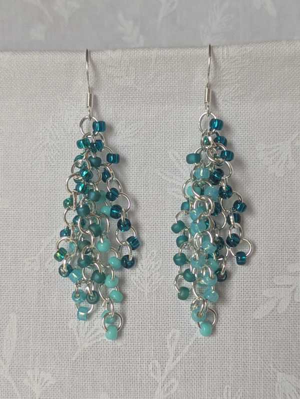 Ocean Depth Earrings featuring 45 glass beads in five teal shades and textures, connected with silver jump rings and sterling silver hooks.