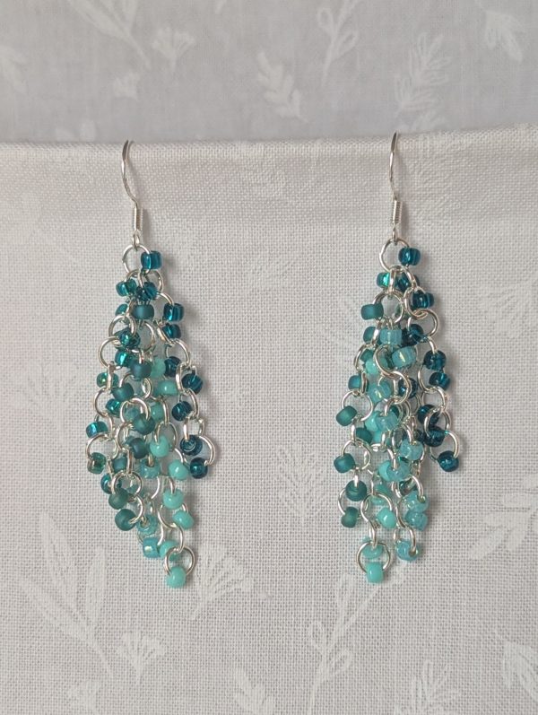 Ocean Depth Earrings featuring 45 glass beads in five teal shades and textures, connected with silver jump rings and sterling silver hooks.