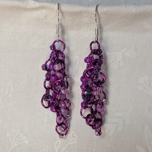 Handmade purple dangle earrings with 24 glass beads in lilac, plum, lavender, and iridescent violet, attached with purple jump rings and sterling silver hooks.