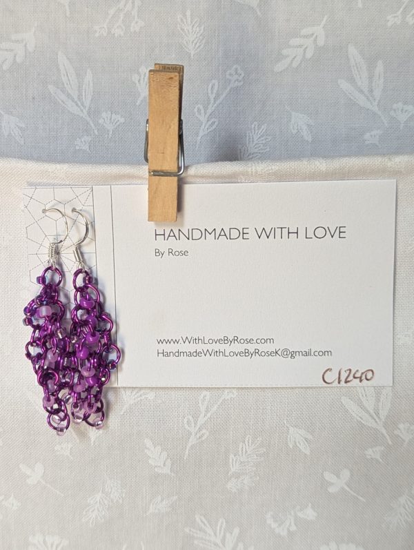 Handmade purple dangle earrings with 24 glass beads in lilac, plum, lavender, and iridescent violet, attached with purple jump rings and sterling silver hooks.