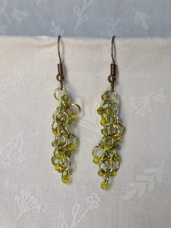 Handmade lime green earrings with 18 assorted green glass beads, lime green jump rings, and antique bronze-colored hooks.