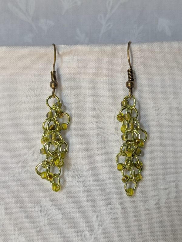 Handmade lime green earrings with 18 assorted green glass beads, lime green jump rings, and antique bronze-colored hooks.