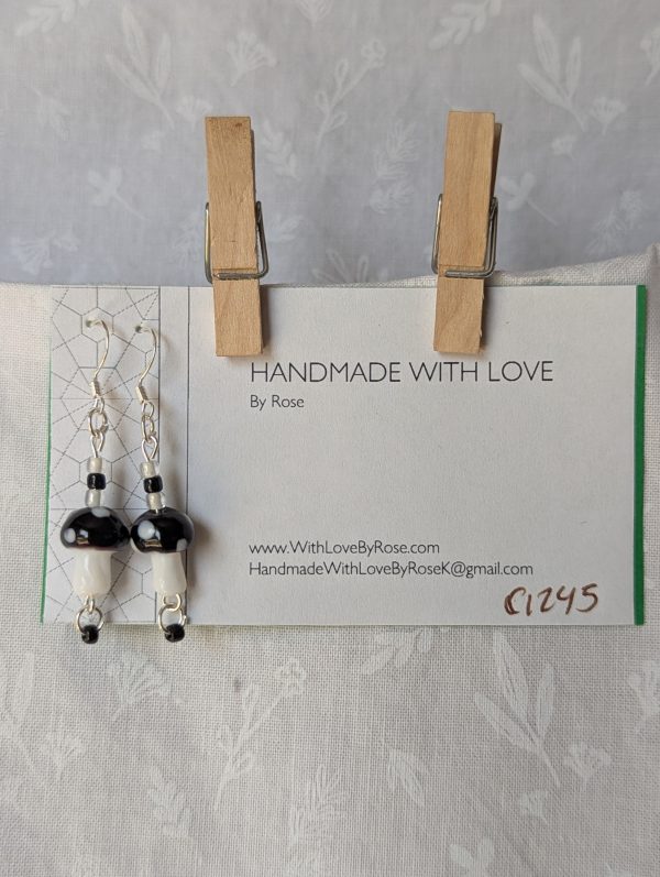 Handmade black mushroom earrings with glass toadstools, black and white seed beads, and sterling silver hooks.