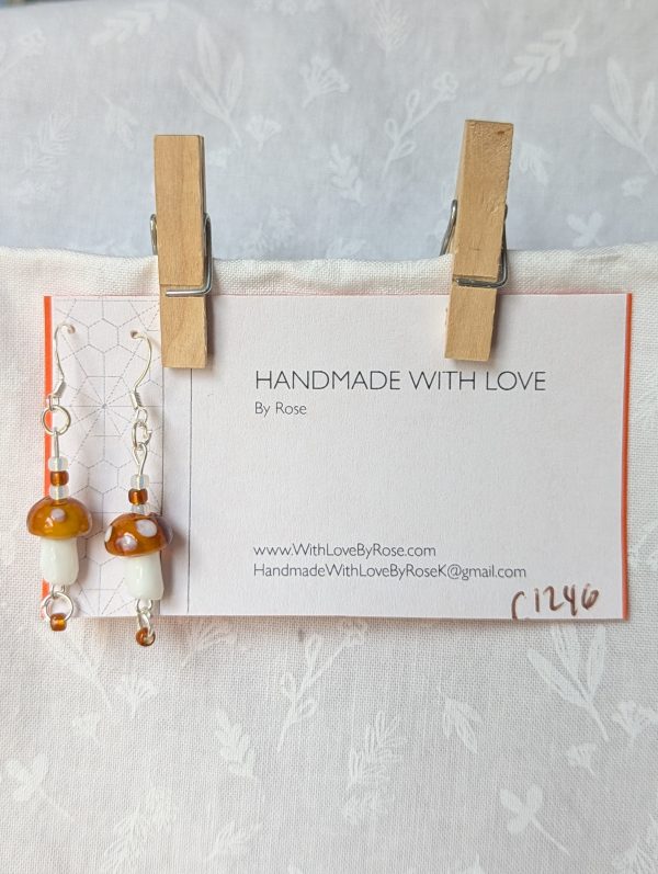 Handmade brown mushroom earrings with glass toadstools, brown and white seed beads, and sterling silver hooks.