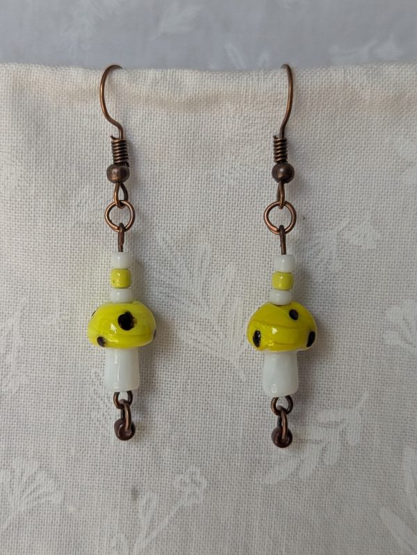 Handmade yellow mushroom earrings with glass toadstools, yellow, brown and white seed beads, and bronze colored hooks.
