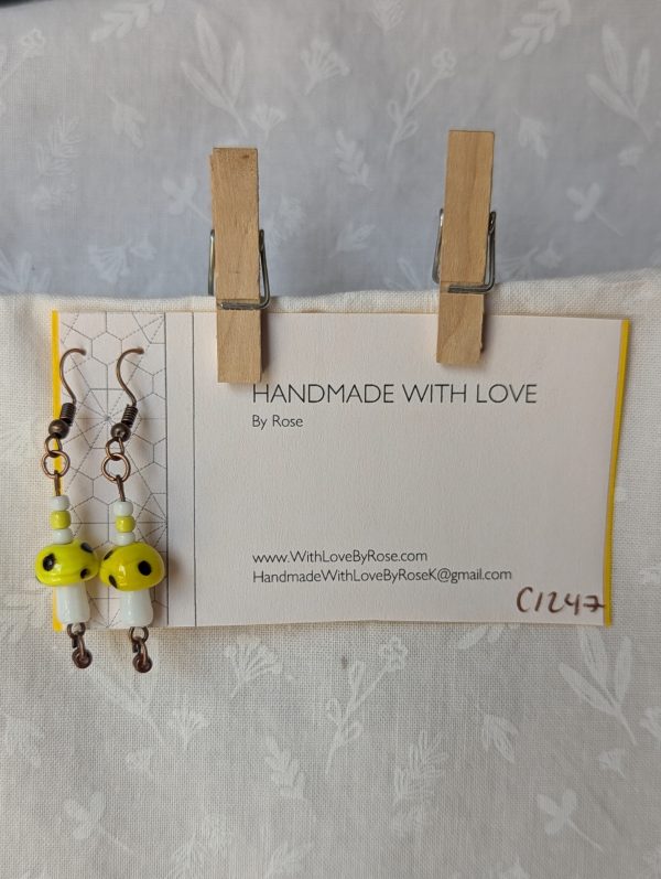 Handmade yellow mushroom earrings with glass toadstools, yellow, brown and white seed beads, and bronze colored hooks.