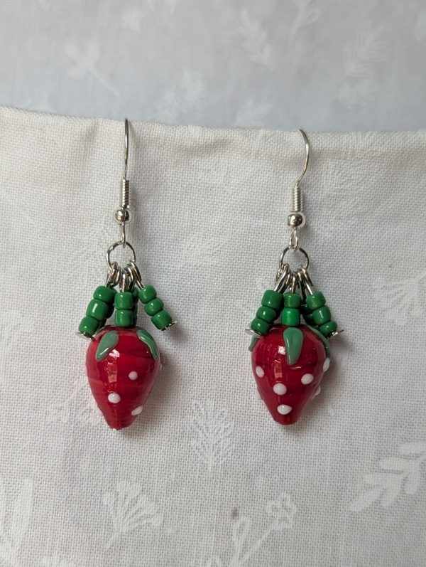 Handmade berry patch strawberry earrings with red and white polka-dotted glass strawberry beads, green seed bead accents, and steel-colored hooks.