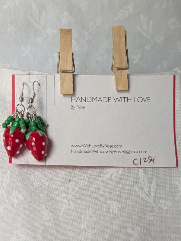 Handmade berry patch strawberry earrings with red and white polka-dotted glass strawberry beads, green seed bead accents, and steel-colored hooks.