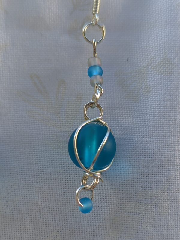 Handmade blue bead earrings with silver wire wrapping, blue and blue-gray seed beads, silver jump rings, and sterling silver hooks.