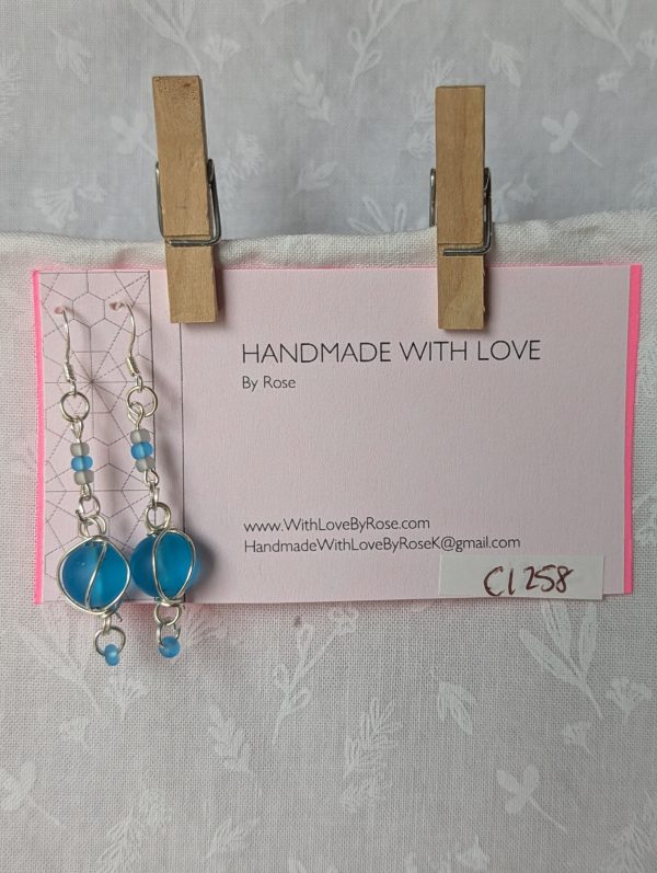Handmade blue bead earrings with silver wire wrapping, blue and blue-gray seed beads, silver jump rings, and sterling silver hooks.