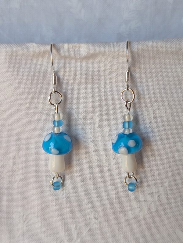Handmade sky-blue mushroom earrings with glass toadstools, sky blue and white seed beads, and sterling silver hooks.