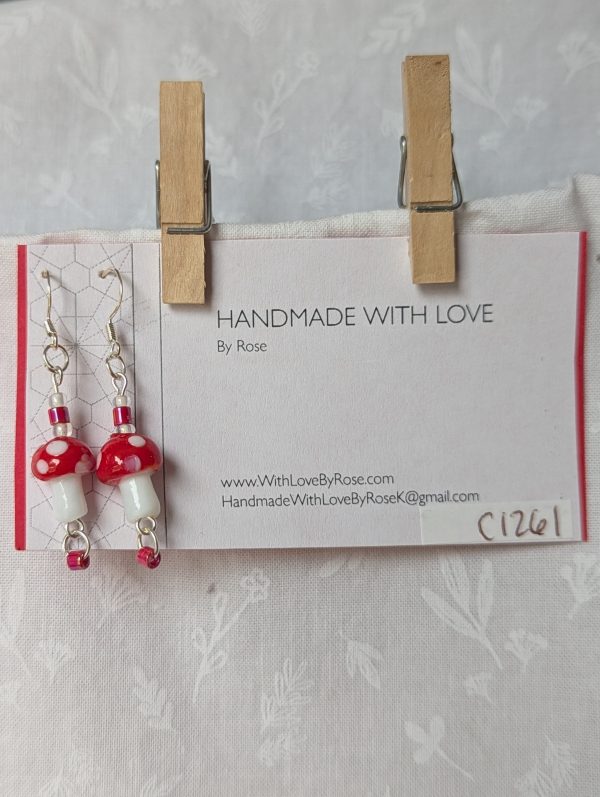 Handmade red mushroom earrings with glass toadstools, red and white seed beads, and sterling silver hooks.