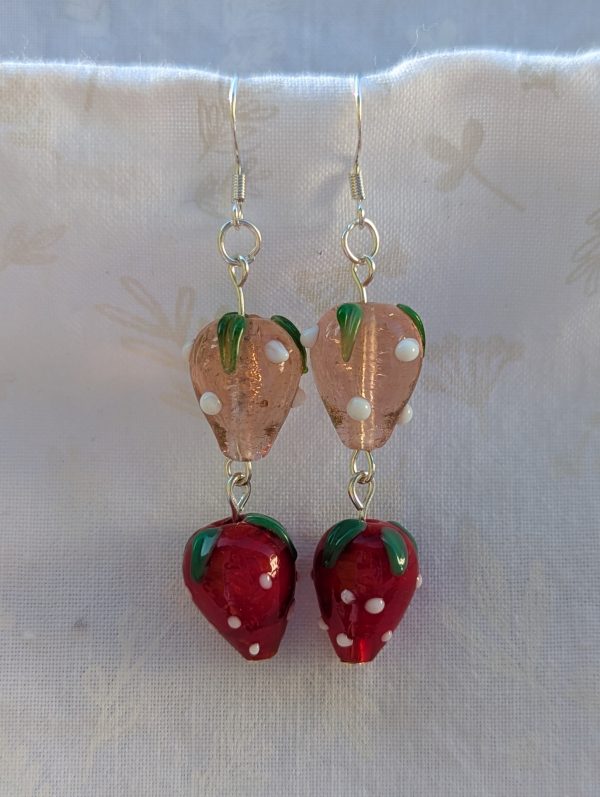 Handmade glass strawberry patch earrings with red, pale pink, green, and white details on sterling silver hooks.