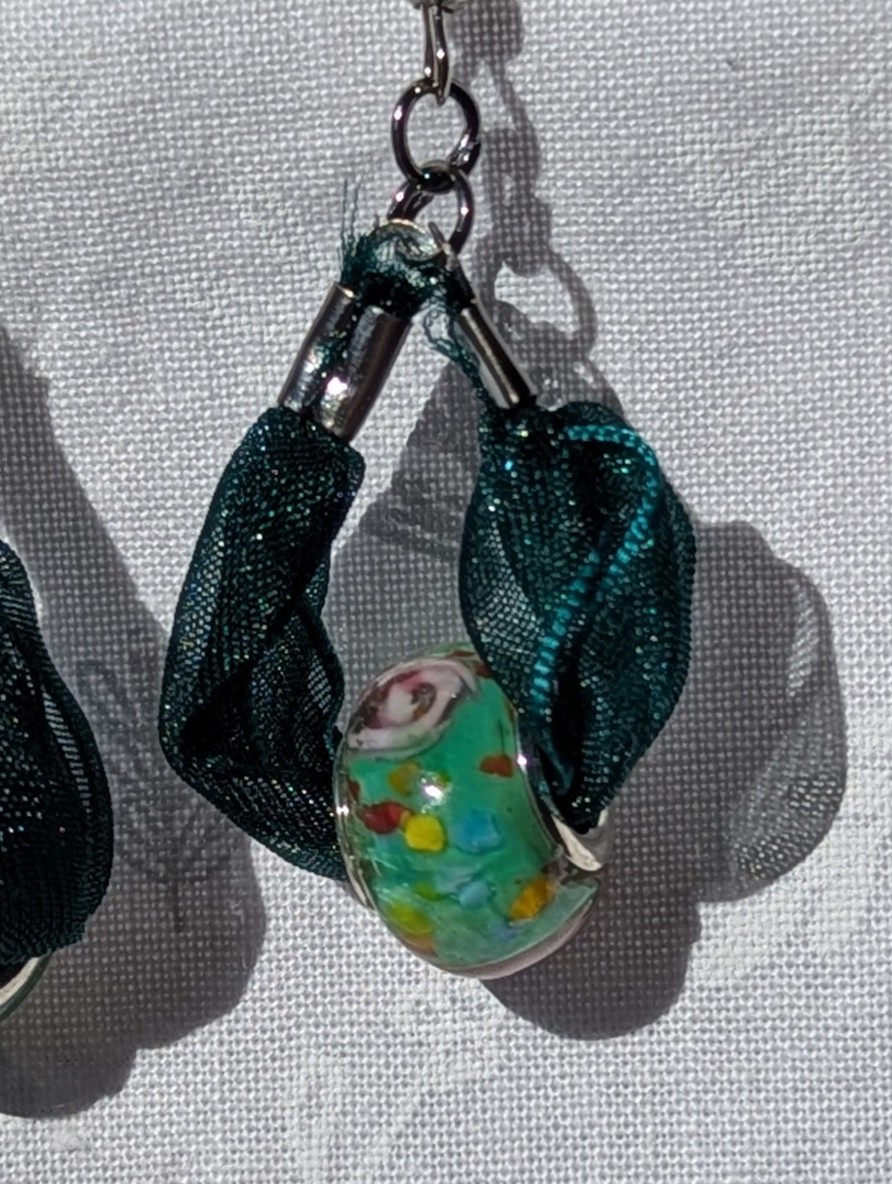 Handmade green ribbon earrings featuring floral glass beads with tungsten metal accents and steel hooks.