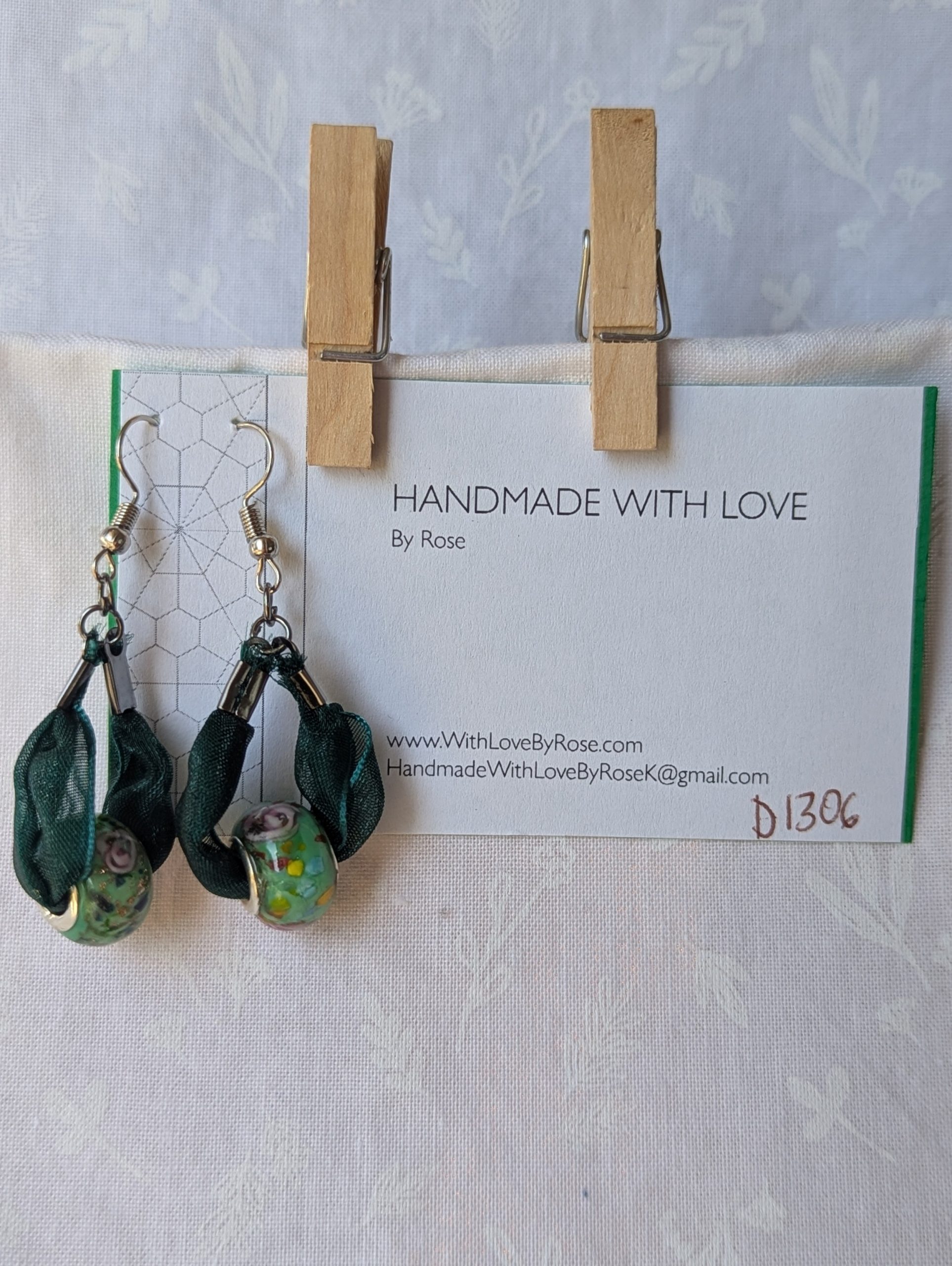 Handmade green ribbon earrings featuring floral glass beads with tungsten metal accents and steel hooks.