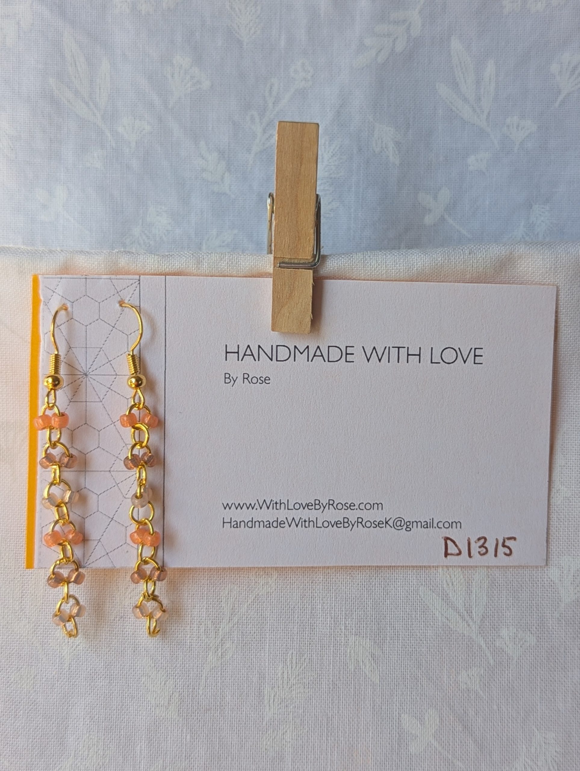 Handmade gold beaded earrings with 12 peach and champagne glass beads connected by gold-colored metal and matching hooks.