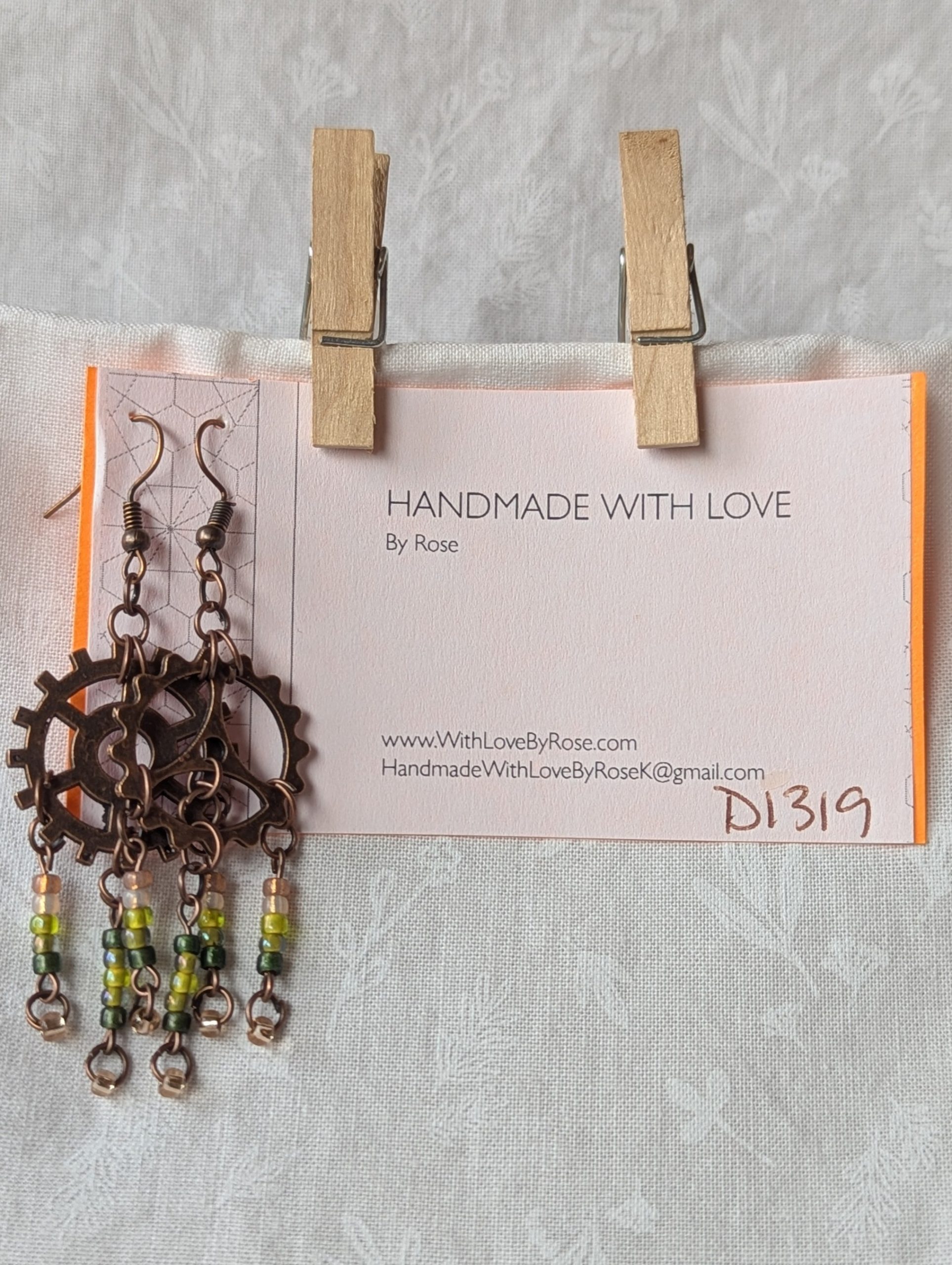 Handmade bronze gear steampunk earrings with green and brown glass beads, asymmetrical steampunk design, and antique bronze hooks.