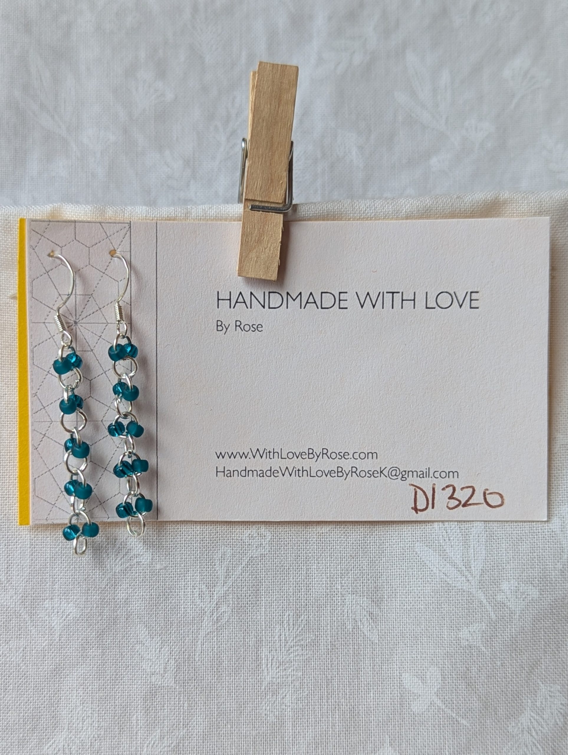 Handmade teal glass earrings featuring frosted and silver-lined teal beads connected with silver jump rings and sterling silver hooks.