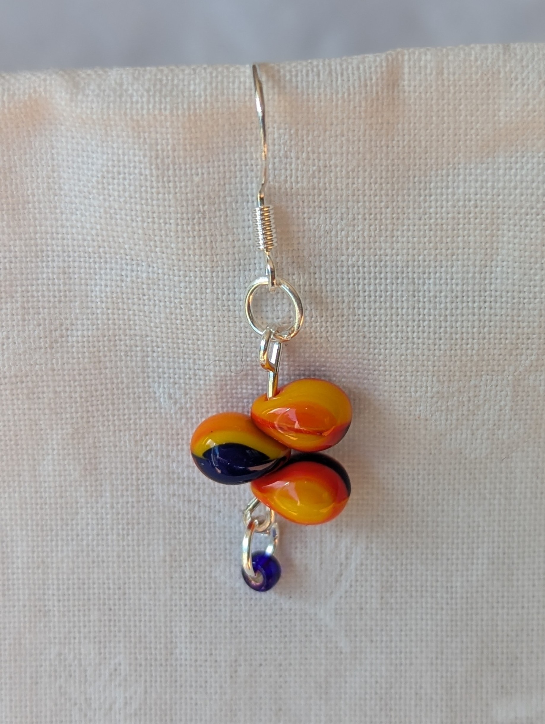 Handmade fireburst trio teardrop glass bead earrings featuring yellow, red, and blue teardrop beads on silver pins with sterling silver hooks.