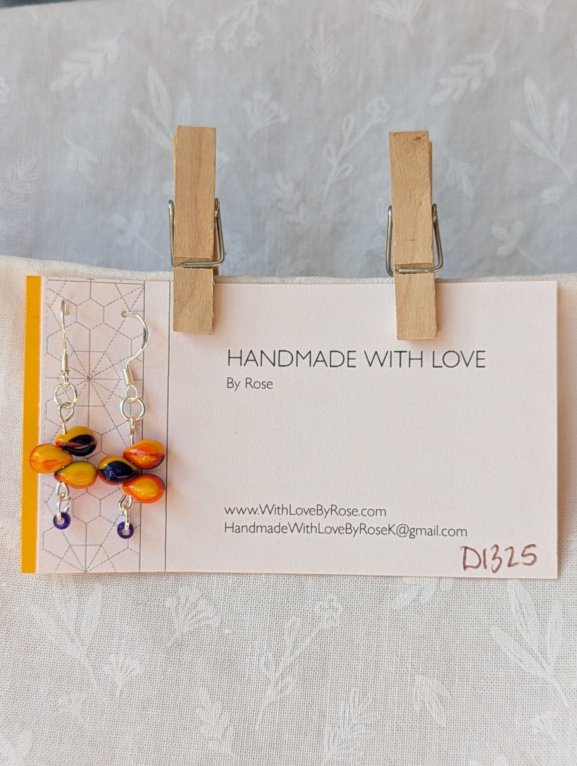 Handmade fireburst trio teardrop glass bead earrings featuring yellow, red, and blue teardrop beads on silver pins with sterling silver hooks.