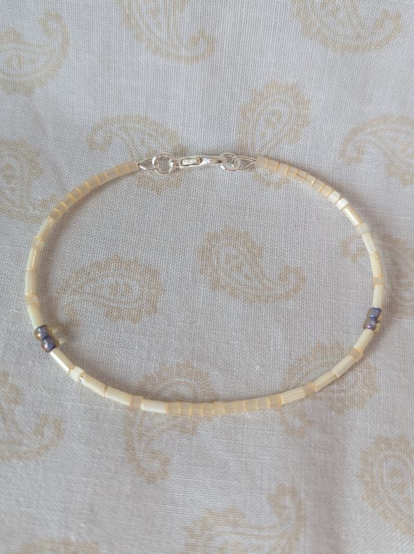 Handmade bracelet with short pearl-cream beads, long ivory-cream beads, and lavender-lined gray beads on silver-plated memory wire with a silver lobster clasp.