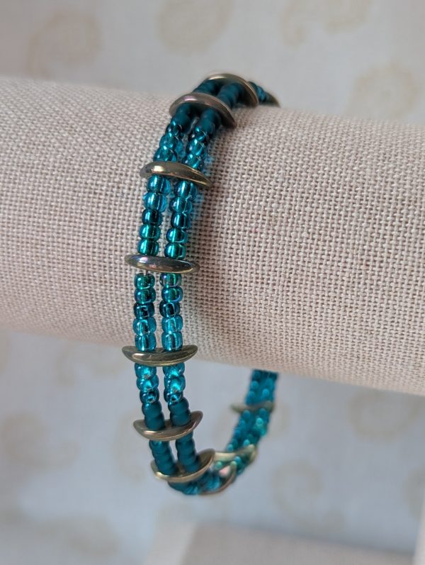 Handmade teal crescent bracelet with layered teal seed beads, metallic crescent beads, and a silver lobster clasp.