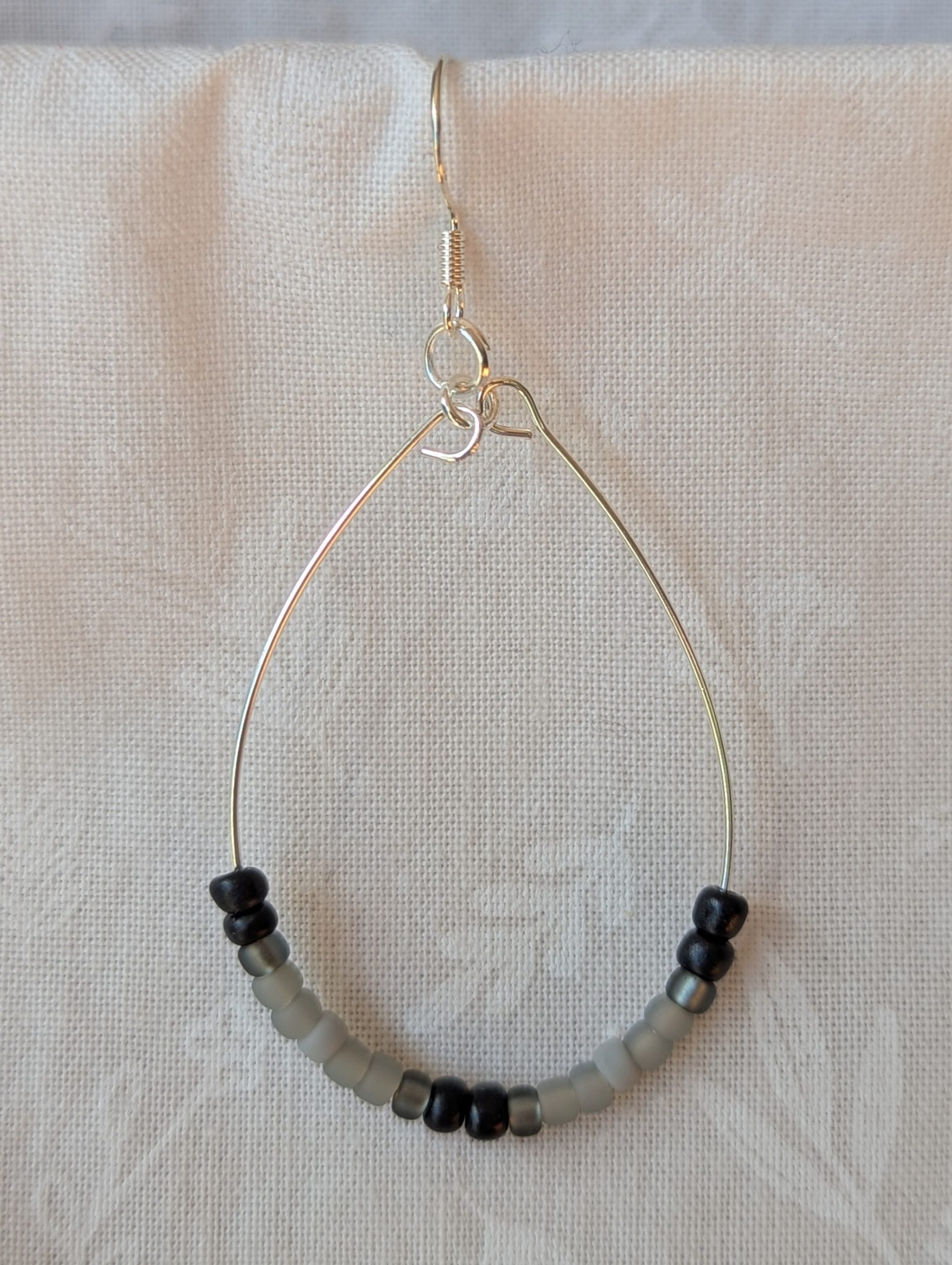 Handmade black and gray monochrome hoop beaded earrings featuring 20 glass beads on silver-plated wire and sterling silver hooks.