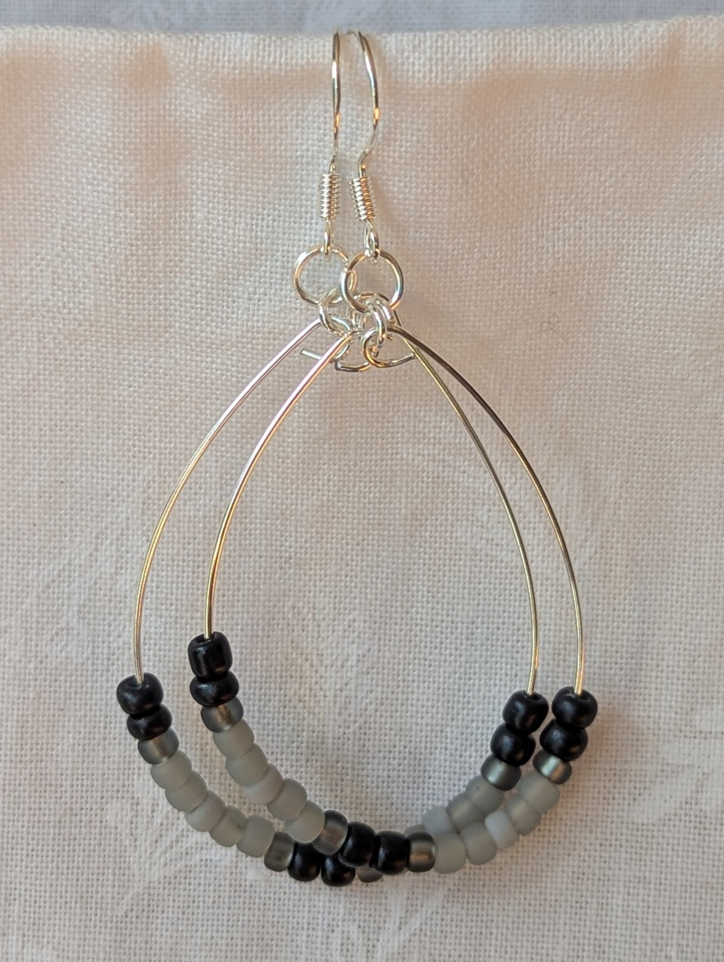 Handmade black and gray monochrome hoop beaded earrings featuring 20 glass beads on silver-plated wire and sterling silver hooks.