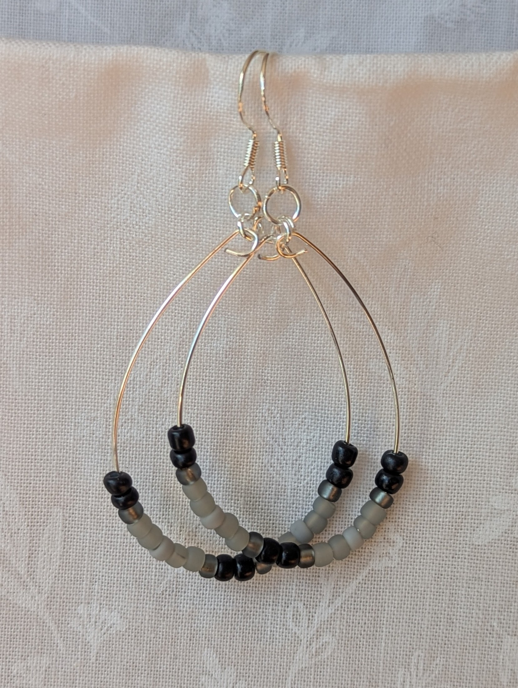 Handmade black and gray monochrome hoop beaded earrings featuring 20 glass beads on silver-plated wire and sterling silver hooks.