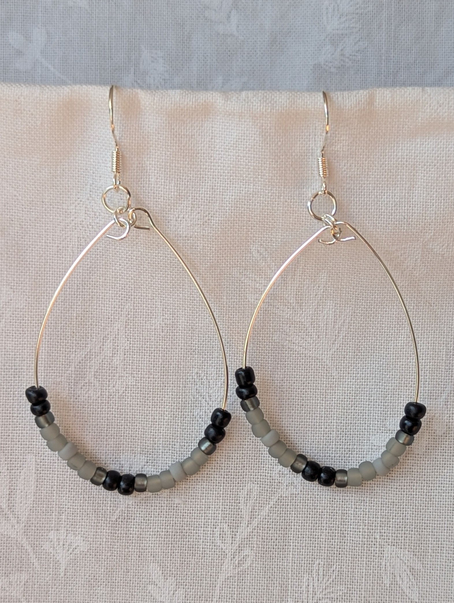 Handmade black and gray monochrome hoop beaded earrings featuring 20 glass beads on silver-plated wire and sterling silver hooks.