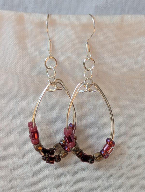 Handmade pink and maroon beaded hoop earrings with 20 glass beads on double hoops of silver-plated wire and sterling silver hooks.