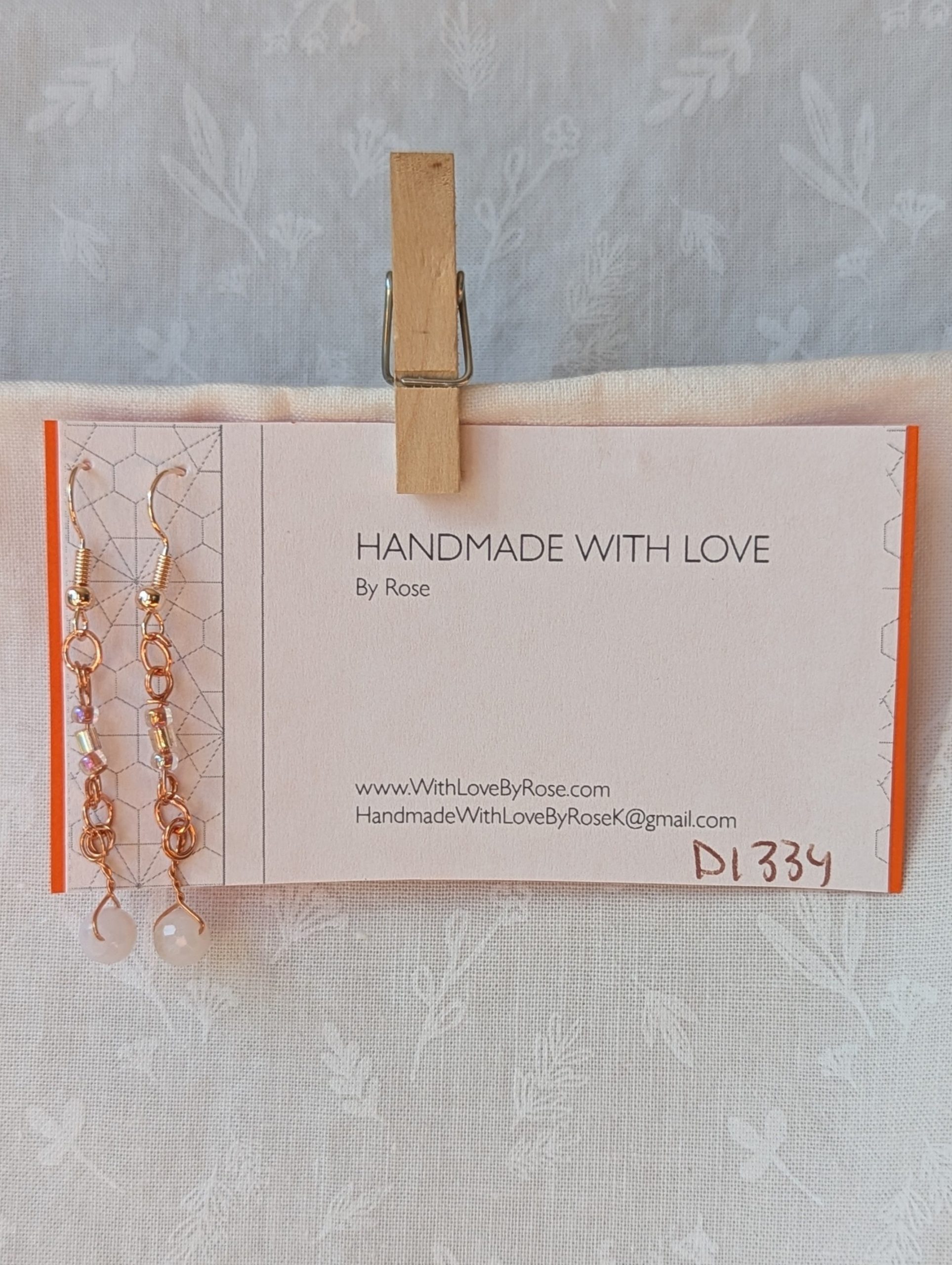 Handmade blush moonlight earrings with white Czech cut beads and pink seed beads wrapped in copper wire on rose-gold hooks.