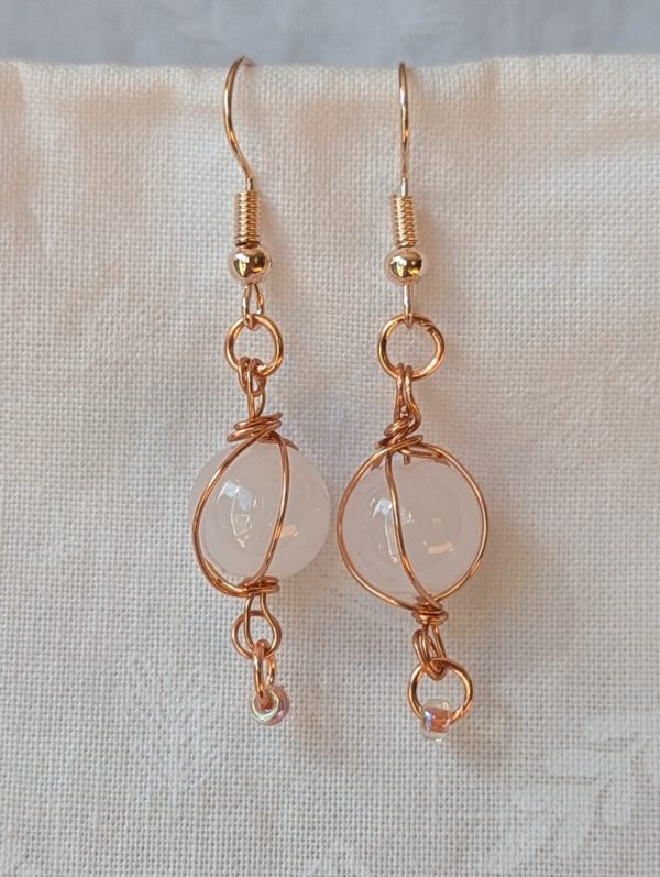 Hand wrapped bead earrings with white glass beads wrapped in copper wire and rose-gold colored hooks.