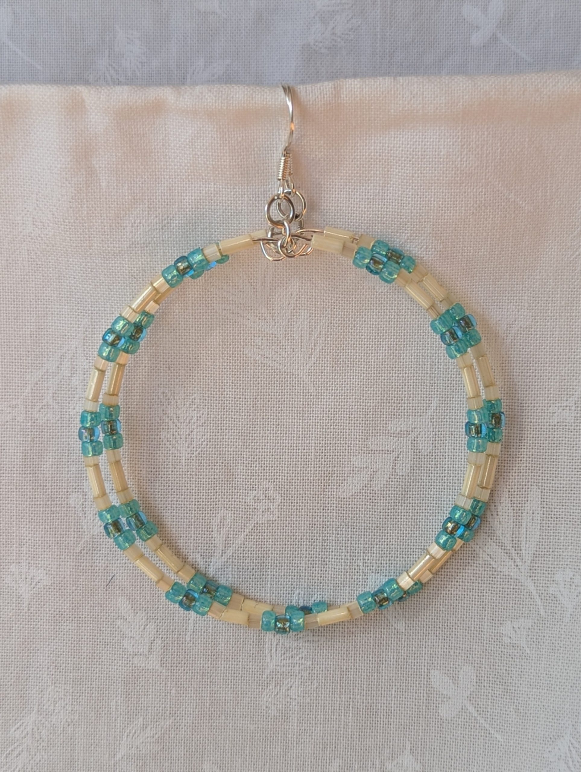 Handmade cream and sky blue beaded hoop earrings with glass beads on silver-plated memory wire and sterling silver hooks.