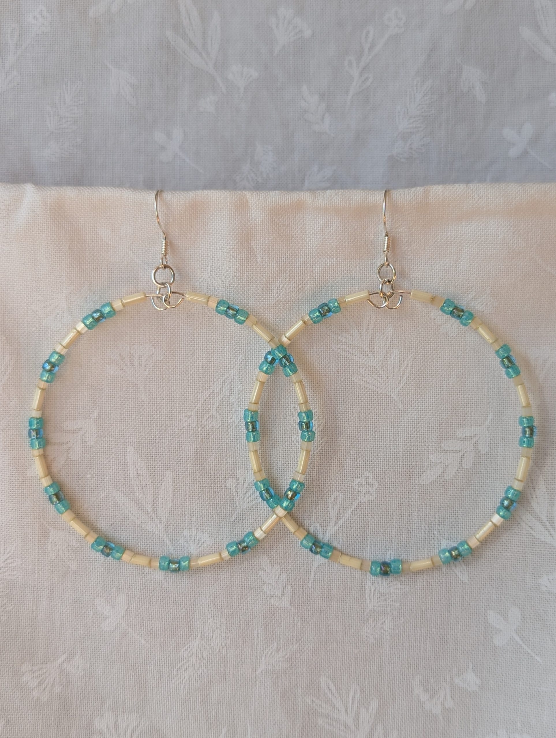 Handmade cream and sky blue beaded hoop earrings with glass beads on silver-plated memory wire and sterling silver hooks.