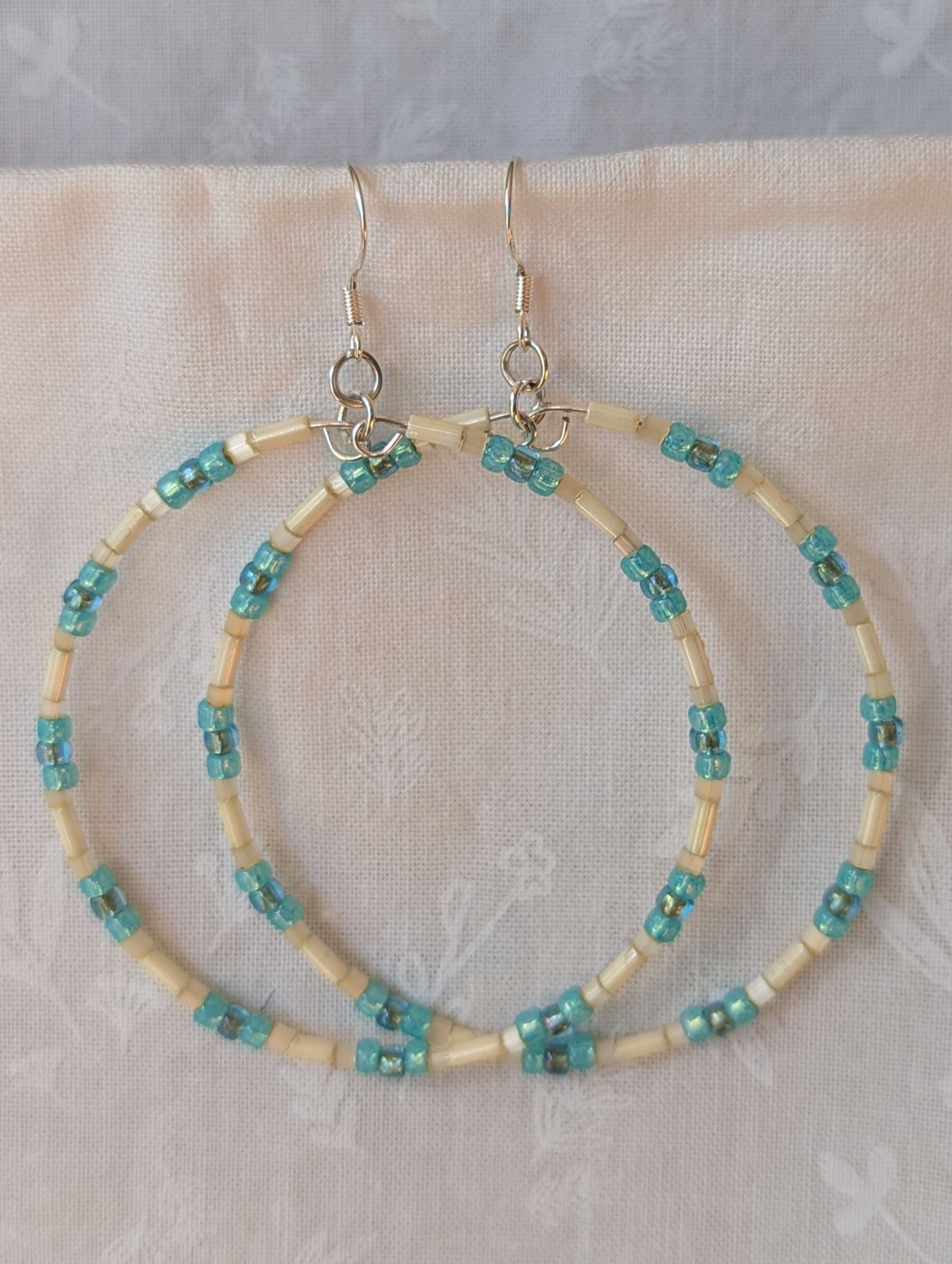 Handmade cream and sky blue beaded hoop earrings with glass beads on silver-plated memory wire and sterling silver hooks.