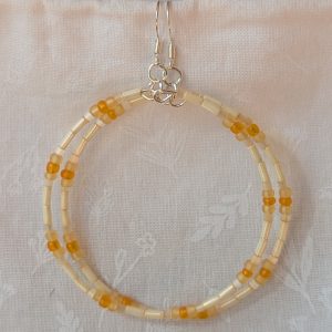 Handmade cream and sunshine yellow/orange beaded hoop earrings with glass beads on silver-plated memory wire and sterling silver hooks.