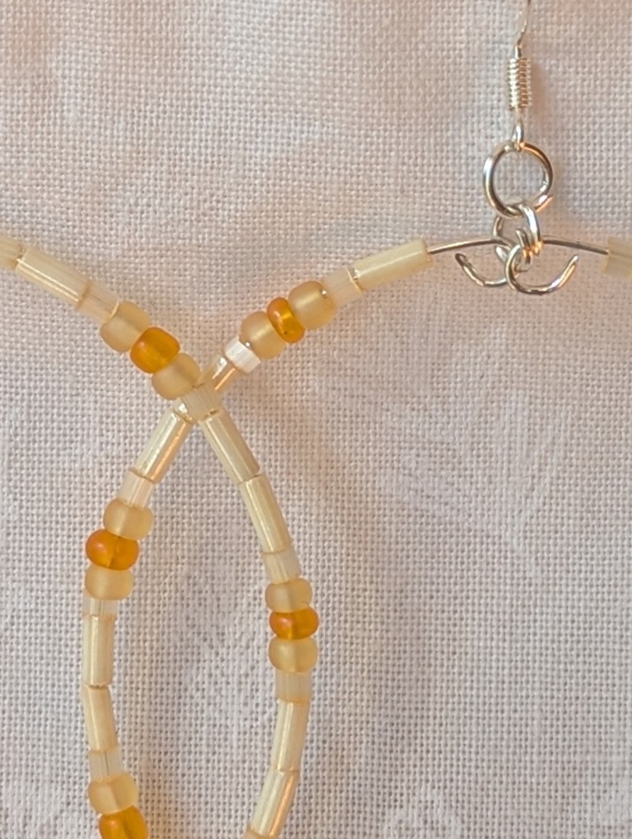 Handmade cream and sunshine yellow/orange beaded hoop earrings with glass beads on silver-plated memory wire and sterling silver hooks.