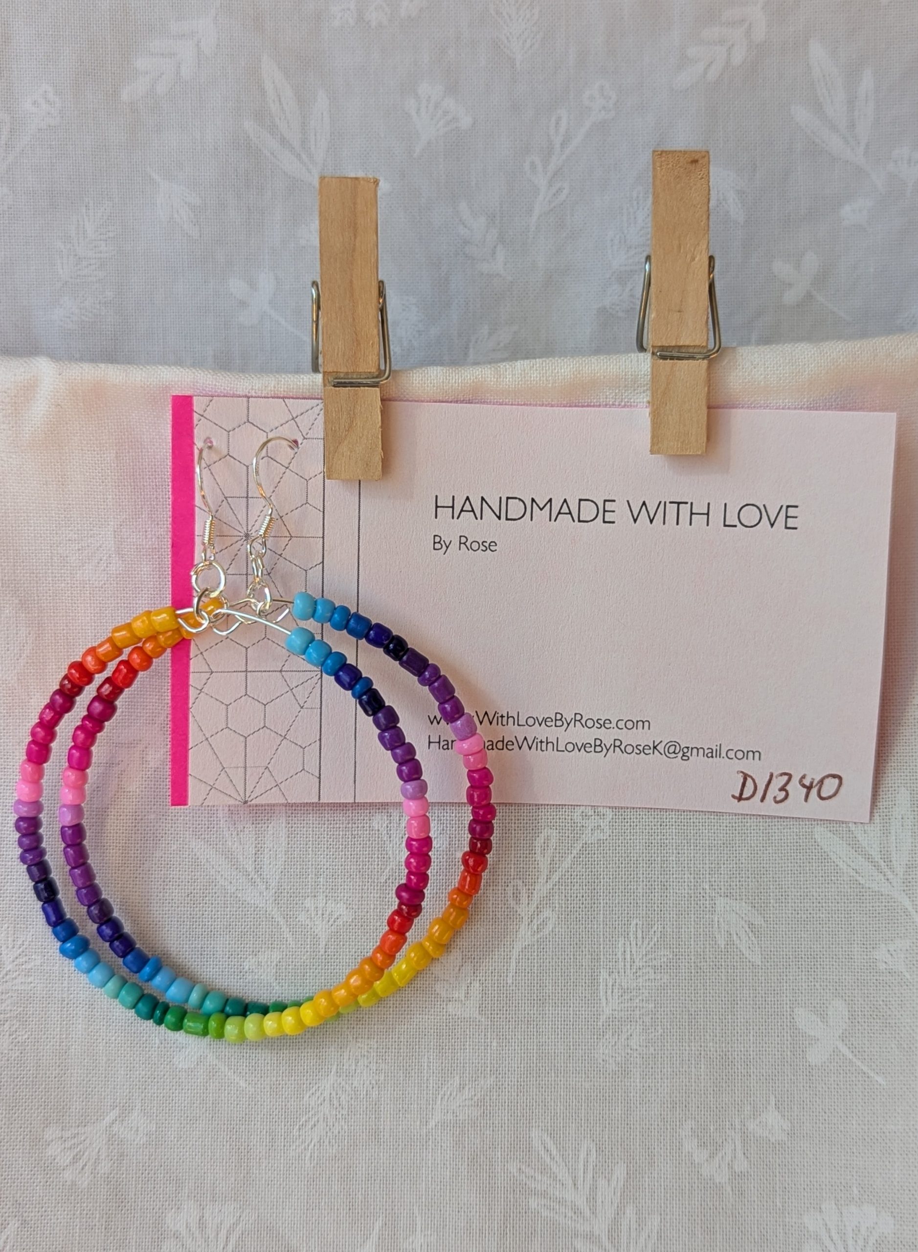 Handmade rainbow hoop earrings with glass seed beads in a full-color gradient on silver-plated memory wire and sterling silver hooks.