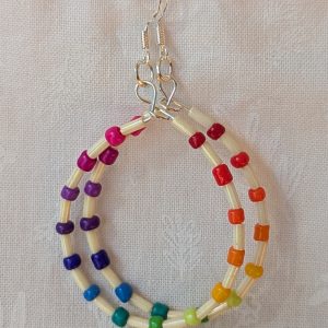 Handmade rainbow and cream accent teardrop shaped loop earrings with alternating colorful glass seed beads and long cream beads on silver-plated wire with sterling silver hooks.