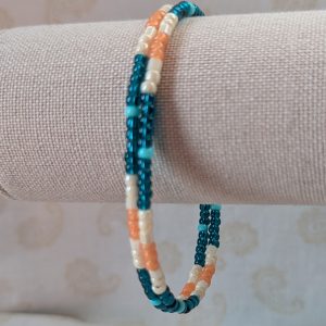 Handmade teal and cream bracelet with salmon and pale teal beads on stretch wire with overlap closure.