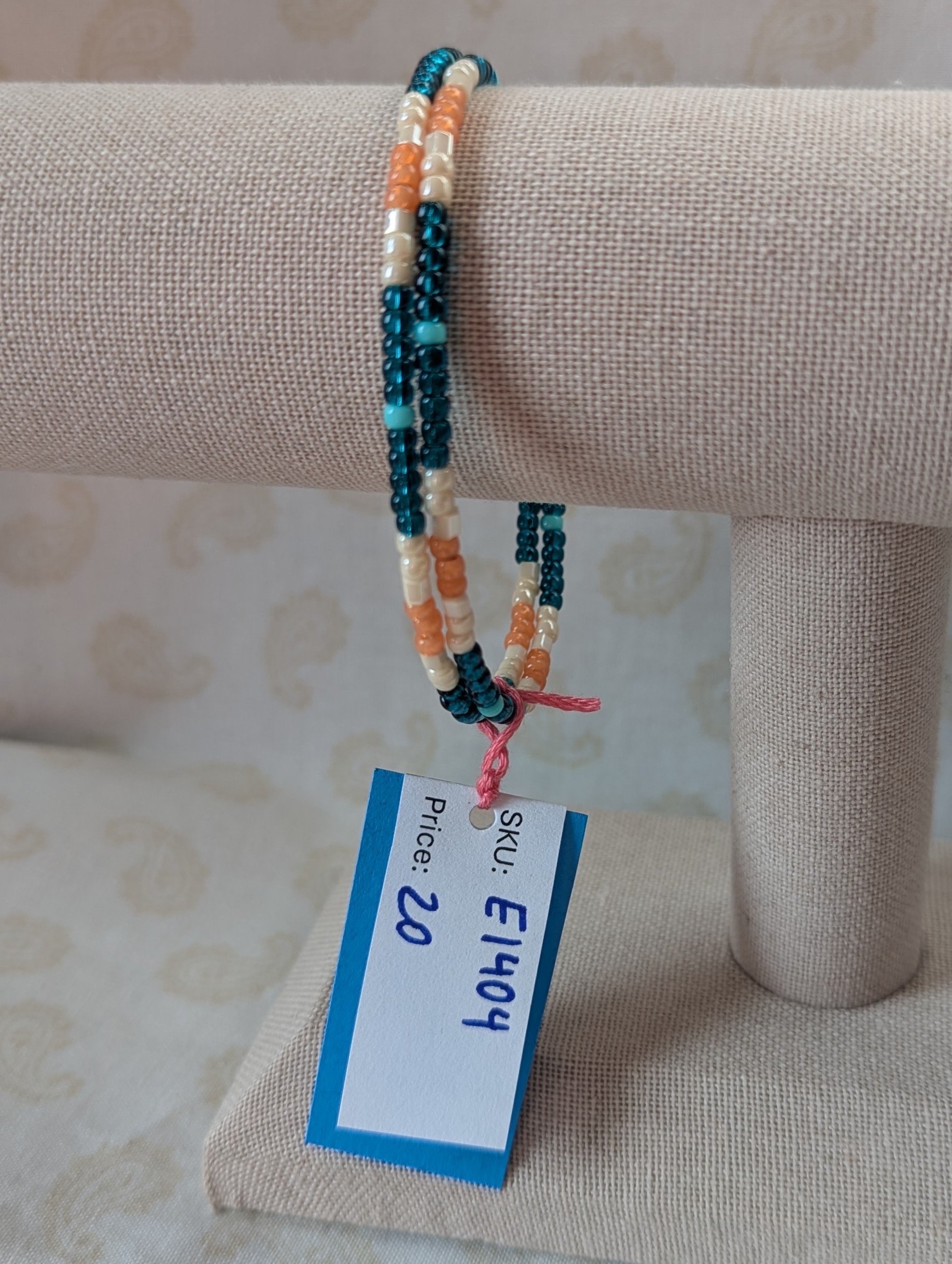Handmade teal and cream bracelet with salmon and pale teal beads on stretch wire with overlap closure.