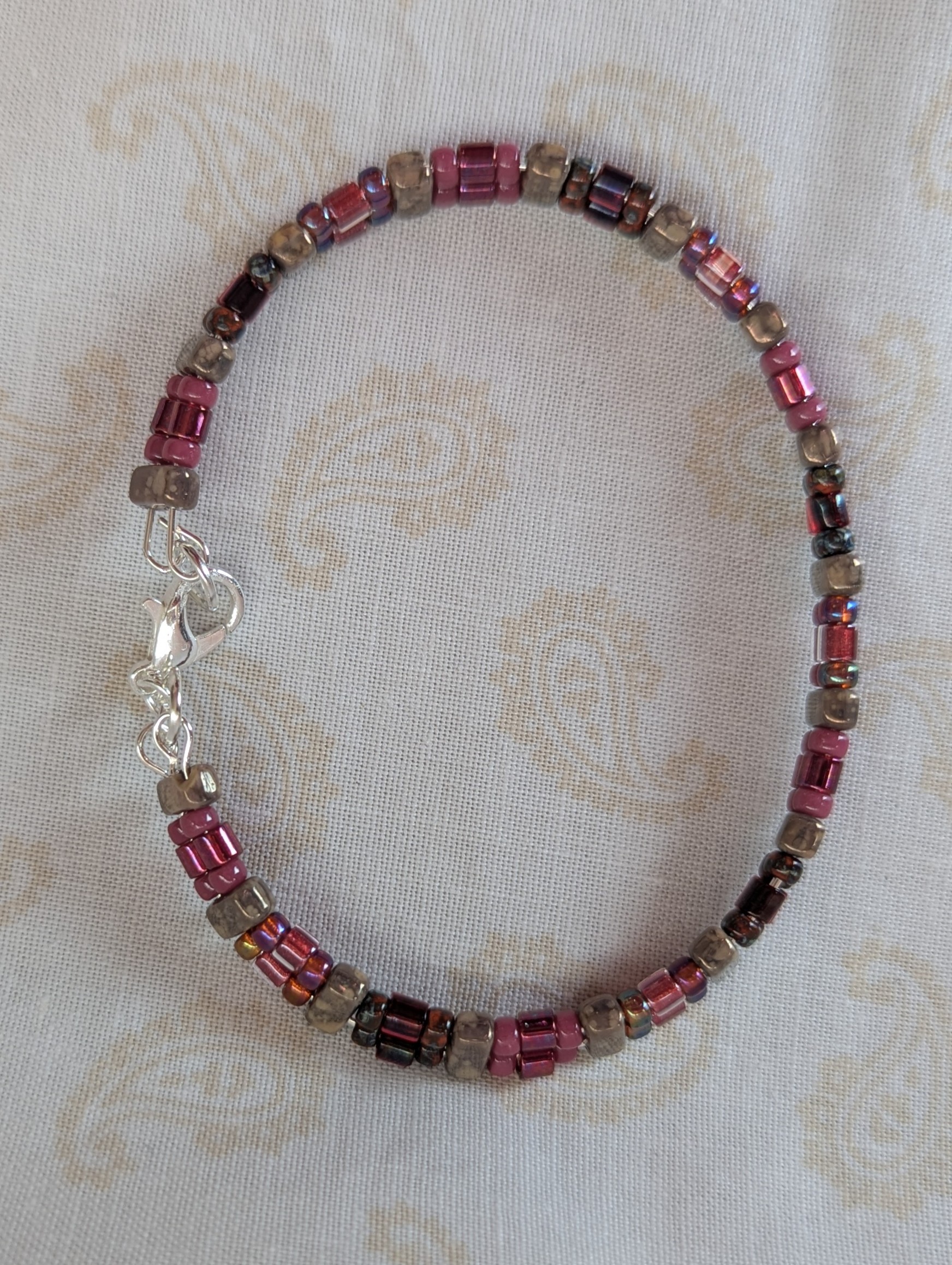 Double-strand memory wire bracelet with rose mauve, garnet, and taupe rectangular stone beads, finished with a silver lobster clasp.