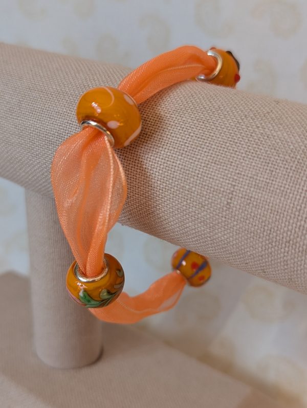 Sunlit Citrus Orange Ribbon Bracelet with sheer orange ribbon, four decorative glass beads in warm citrus tones, and silver lobster clasp