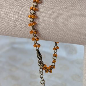 Orange seed bead bracelet with hand-linked bronze chain, matte and silver-lined orange beads, and bronze lobster clasp