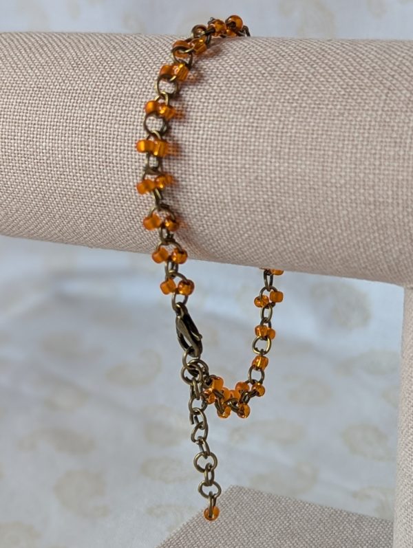 Orange seed bead bracelet with hand-linked bronze chain, matte and silver-lined orange beads, and bronze lobster clasp
