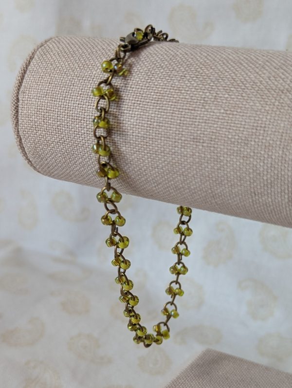 Bronze chain bracelet with paired green seed beads, featuring pink-lined green and silver-lined olive glass beads and a bronze lobster clasp.