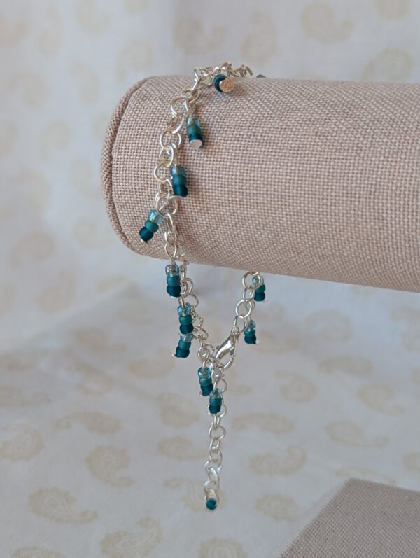 Silver chain bracelet with dangling teal gradient seed bead trios in deep ocean blue, sea green, and soft aqua, finished with a silver lobster clasp.
